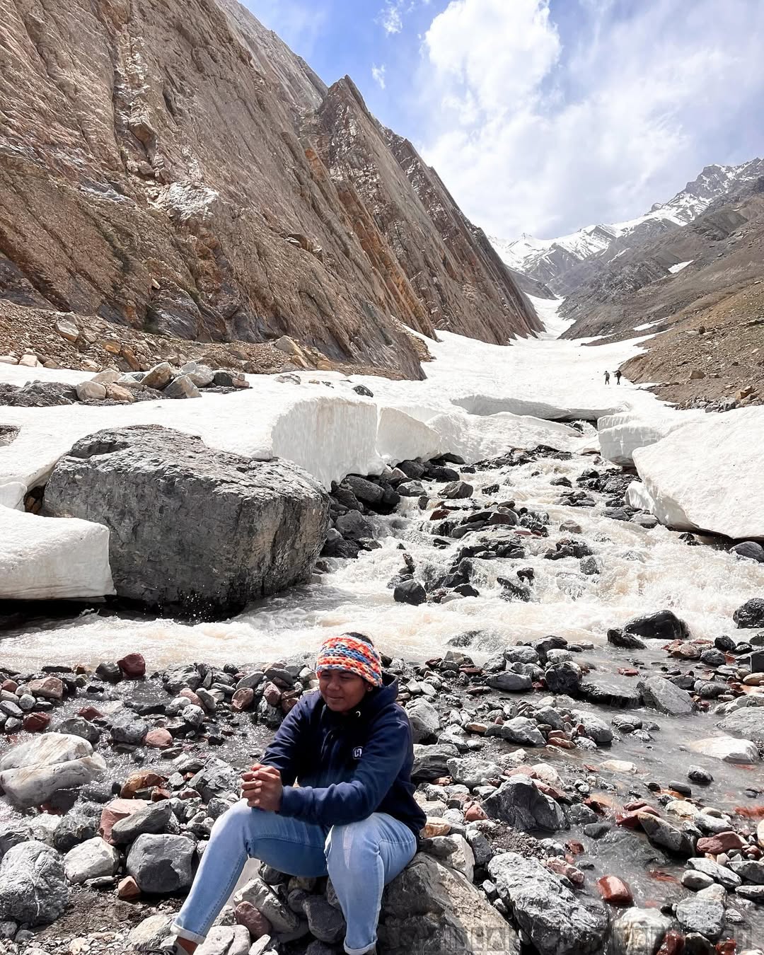 Thenmozhi sitting beside a rocky snowmelt stream in Pin Valley, Spiti.